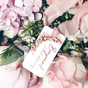 May include: A white gift tag with a pink floral border and the text "Happy Flowers!" in red cursive. The tag is attached to a bouquet of pink flowers.