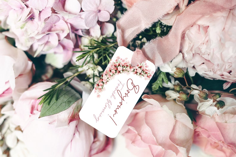 May include: A white gift tag with a pink floral border and the text "Happy Flowers!" in red cursive. The tag is attached to a bouquet of pink flowers.