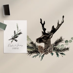 Puede incluir: Una ilustraci&oacute;n de acuarela de una cabeza de ciervo negra con cuernos, rodeada de ramas de pino verdes y pi&ntilde;as. El texto "Chic Black Christmas Object" est&aacute; escrito en cursiva verde en el lado derecho de la imagen.