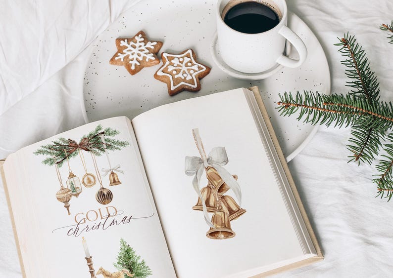 May include: An open book featuring watercolor illustrations of gold Christmas ornaments, bells, and pine branches, with the text "GOLD christmas" printed on the left page, accompanied by a white mug of coffee and two star-shaped cookies.