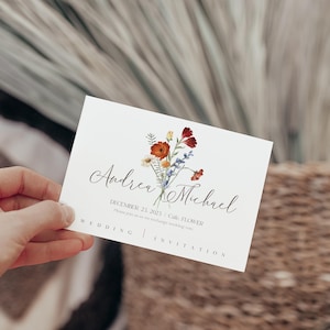 May include: A white wedding invitation card with the names "Andrea & Michael" in elegant script, adorned with a floral bouquet. The card includes the date "December 21, 2021" and the words "Wedding Invitation".