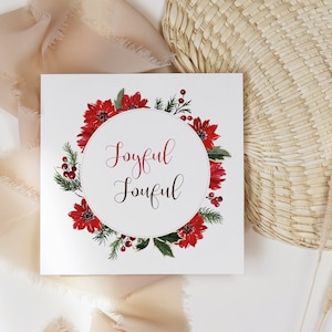 K&ouml;nnte beinhalten: Eine wei&szlig;e Karte mit einem roten Weihnachtsstern-Kranz und den Worten "Joyful Joyful" in einem Kreis.
