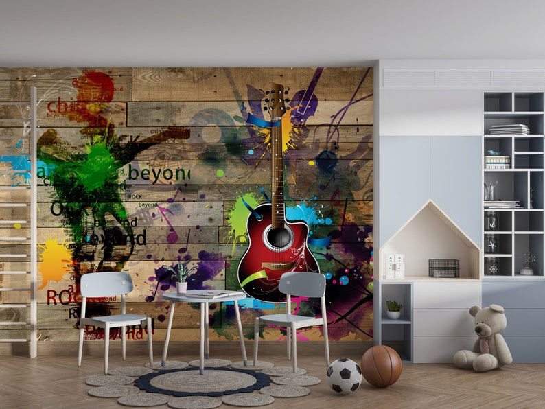 Op de afbeelding: Een kleurrijke muurschildering met een rode akoestische gitaar, muzieknoten en de woorden "rock beyond" en "rock". De muurschildering bevindt zich in een kamer met een houten vloer, een bruin tapijt en twee stoelen.