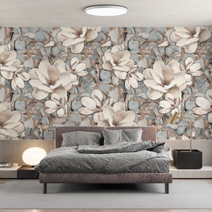 May include: A bedroom with a gray bed and white bedding. The wall behind the bed is covered in a wallpaper with a floral pattern of white flowers on a blue and brown background.