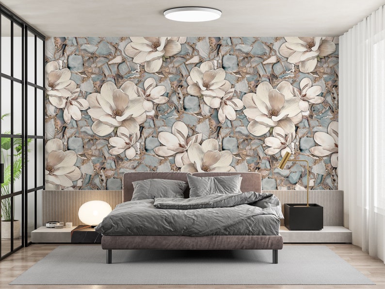 May include: A bedroom with a gray bed and white bedding. The wall behind the bed is covered in a wallpaper with a floral pattern of white flowers on a blue and brown background.
