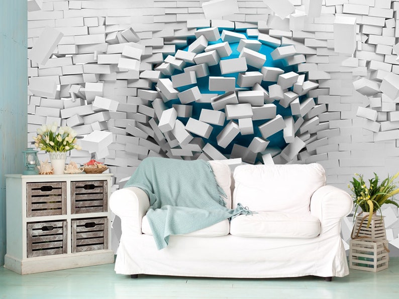 May include: A white brick wall with a blue sphere breaking through the center. The sphere is surrounded by white bricks that are falling away from the wall.