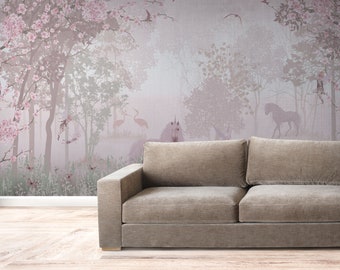 May include: A light pink and gray wallpaper mural with a whimsical forest scene featuring a unicorn, birds, and trees. The mural is displayed in a room with a brown couch in front of it.
