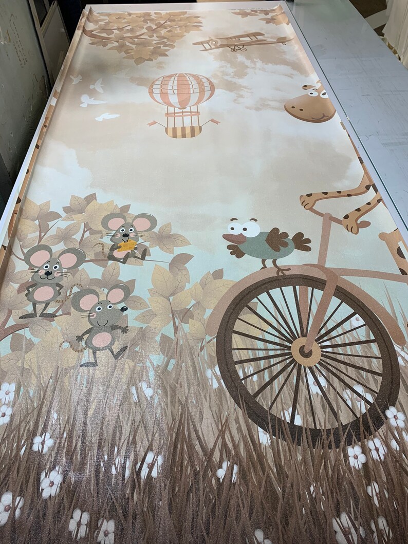 May include: A beige and brown wallpaper with a whimsical design featuring a hot air balloon, a plane, a giraffe riding a bicycle, a bird, and three mice. The wallpaper has a textured, fabric-like appearance.