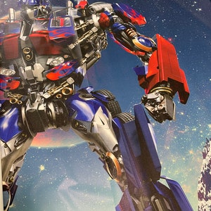 Puede incluir: Un robot azul y rojo con un brazo grande y poderoso se levanta contra un cielo nocturno estrellado. El robot tiene una cabeza grande y redonda con un solo ojo y una boca abierta de par en par. El cuerpo del robot est&aacute; cubierto de detalles y marcas intrincadas.