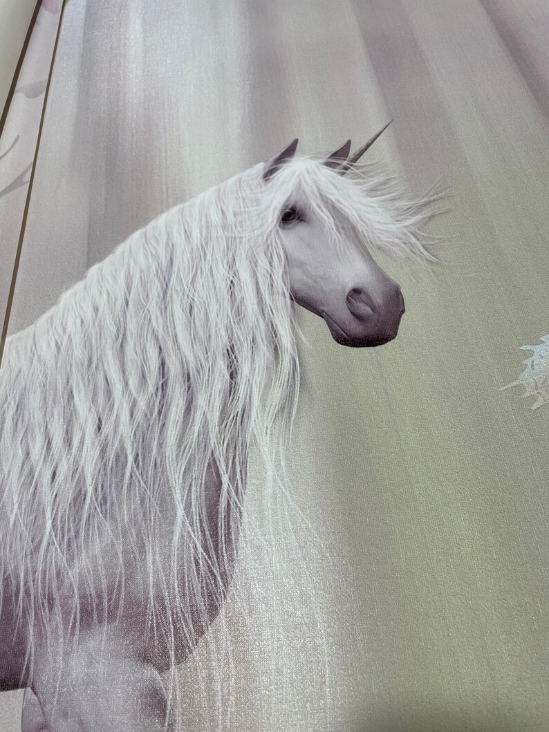 May include: A white unicorn with a long flowing mane and tail stands against a light gray and green background. The unicorn's horn is visible and its head is turned to the side.