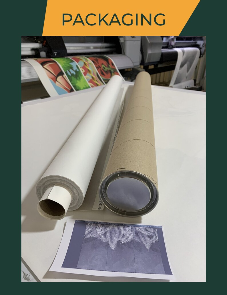 May include: Two rolled canvases are being packaged in cardboard tubes. One canvas is white and the other is printed with a colorful design. The tubes are on a white surface.