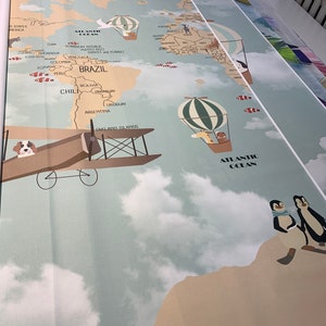 Puede incluir: Un mapa del mundo azul claro y beige con un cielo azul claro y nubes blancas. El mapa presenta un globo aerost&aacute;tico, un biplano y ping&uuml;inos. El mapa incluye el texto "ATLANTIC OCEAN".