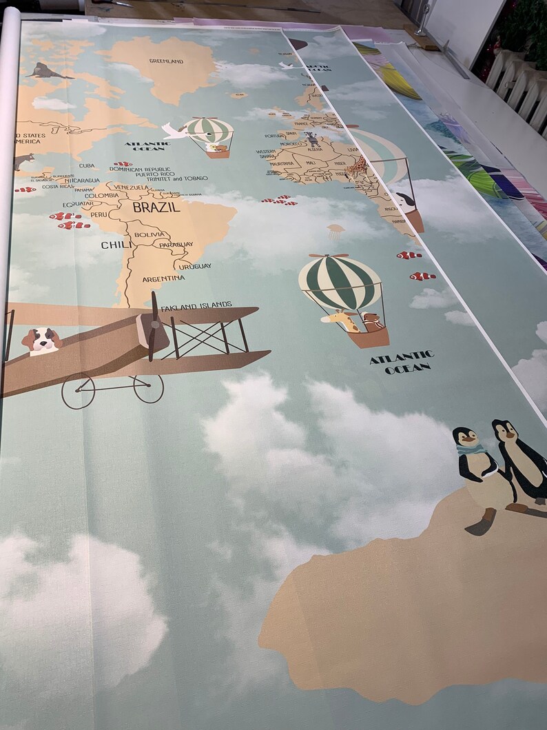 Puede incluir: Un mapa del mundo azul claro y beige con un cielo azul claro y nubes blancas. El mapa presenta un globo aerost&aacute;tico, un biplano y ping&uuml;inos. El mapa incluye el texto "ATLANTIC OCEAN".