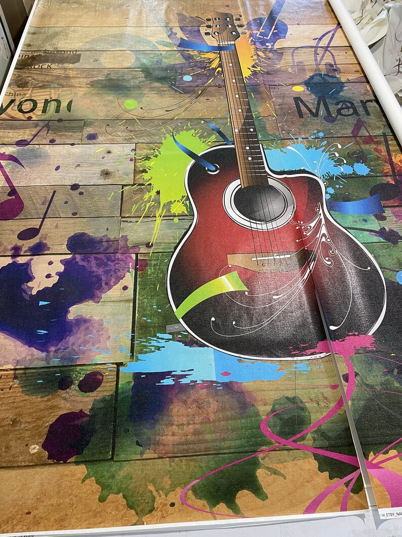 Op de afbeelding: Een rode akoestische gitaar met zwarte en witte details is geschilderd op een houten achtergrond met kleurrijke verfspatten. De woorden "Rock" en "Mar" zijn zichtbaar op de achtergrond.