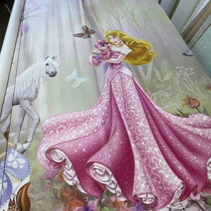 May include: A pink and white princess dress with a white unicorn and a small pink bird in the background. The dress has a sparkly design and a flowing skirt.