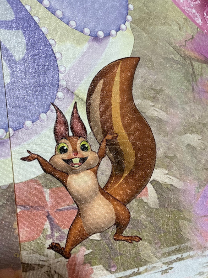 May include: A cartoon squirrel with brown fur and a bushy tail stands on its hind legs with its arms outstretched. The squirrel has a wide smile and large, round eyes. The background is a blurred image of a purple and white fabric.