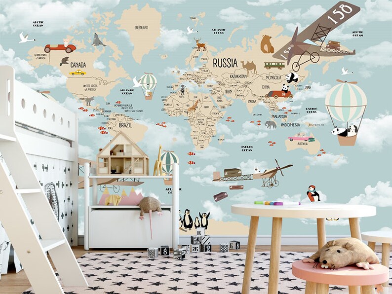 Puede incluir: Un mural de papel tapiz de mapa del mundo de color azul claro y beige con un dise&ntilde;o caprichoso que presenta animales, aviones, globos aerost&aacute;ticos y autom&oacute;viles. El mapa incluye nombres de pa&iacute;ses como Canad&aacute;, Rusia, Brasil e Indonesia.