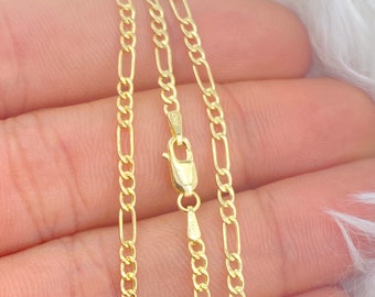 Op de afbeelding: Een gouden ketting met een figaro-kettingontwerp. De ketting wordt op een hand getoond, met de sluiting zichtbaar.