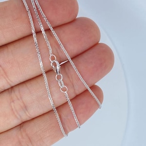 May include: A silver chain necklace with a lobster clasp closure. The chain is a delicate, braided design.