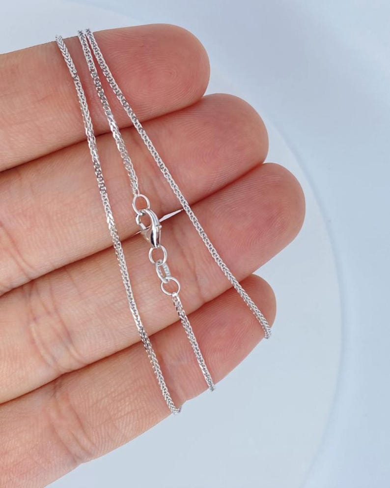 May include: A silver chain necklace with a lobster clasp closure. The chain is a delicate, braided design.