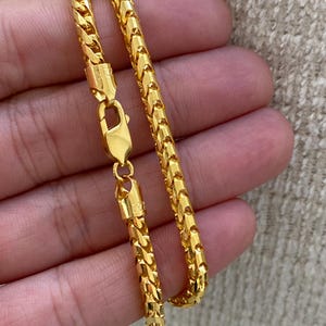 May include: A gold chain necklace with a box clasp. The chain is made of a series of small, interlocking links.