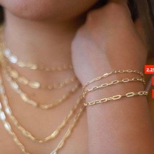 Pu&ograve; includere: Tre braccialetti a catena d'oro in diverse dimensioni, 2,25 mm, 3 mm e 4 mm. I braccialetti sono mostrati sul polso di una persona.