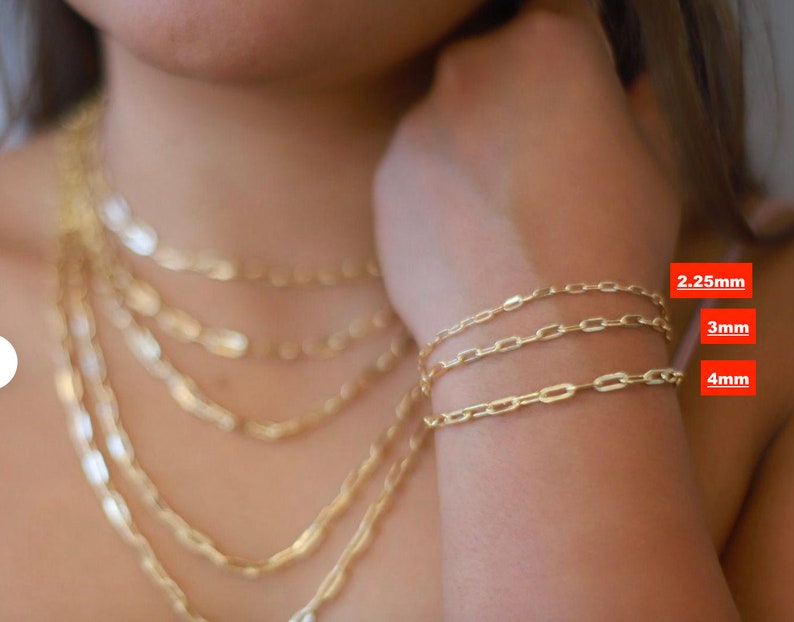 Pu&ograve; includere: Tre braccialetti a catena d'oro in diverse dimensioni, 2,25 mm, 3 mm e 4 mm. I braccialetti sono mostrati sul polso di una persona.