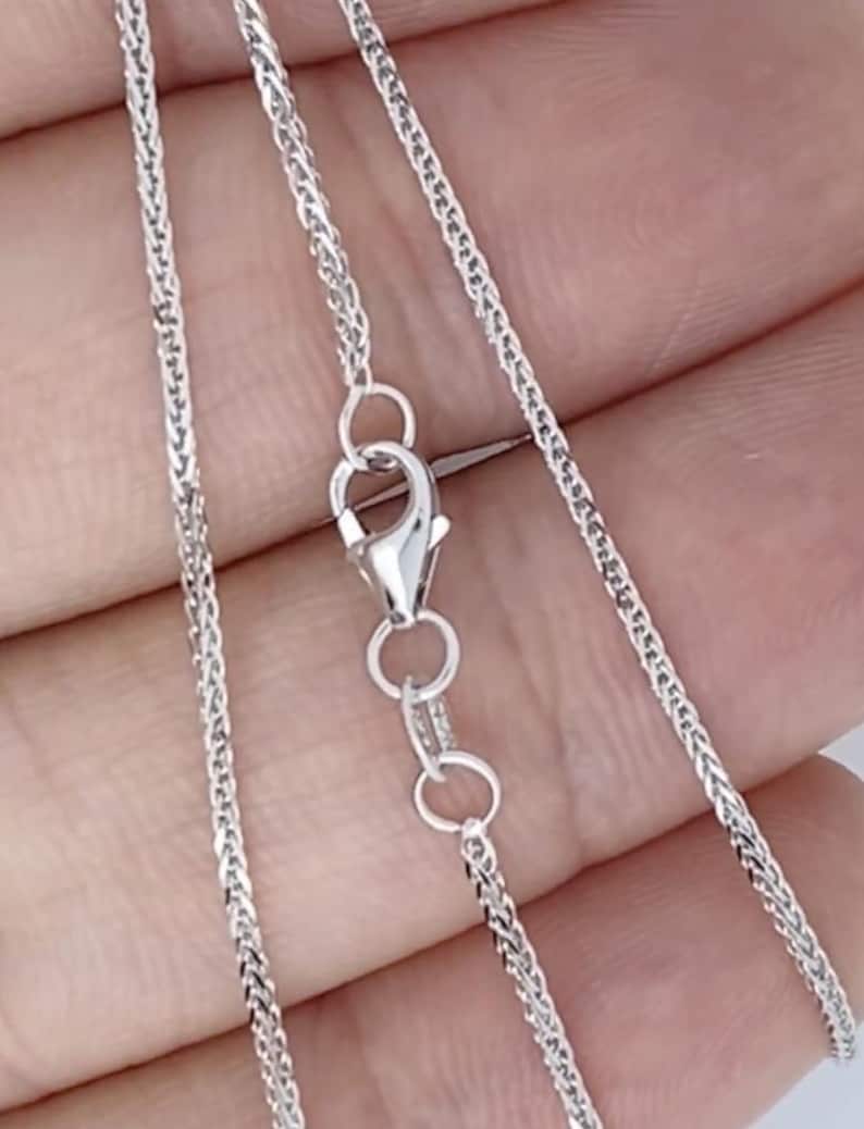 May include: A silver chain necklace with a lobster clasp. The chain is a delicate, braided design.