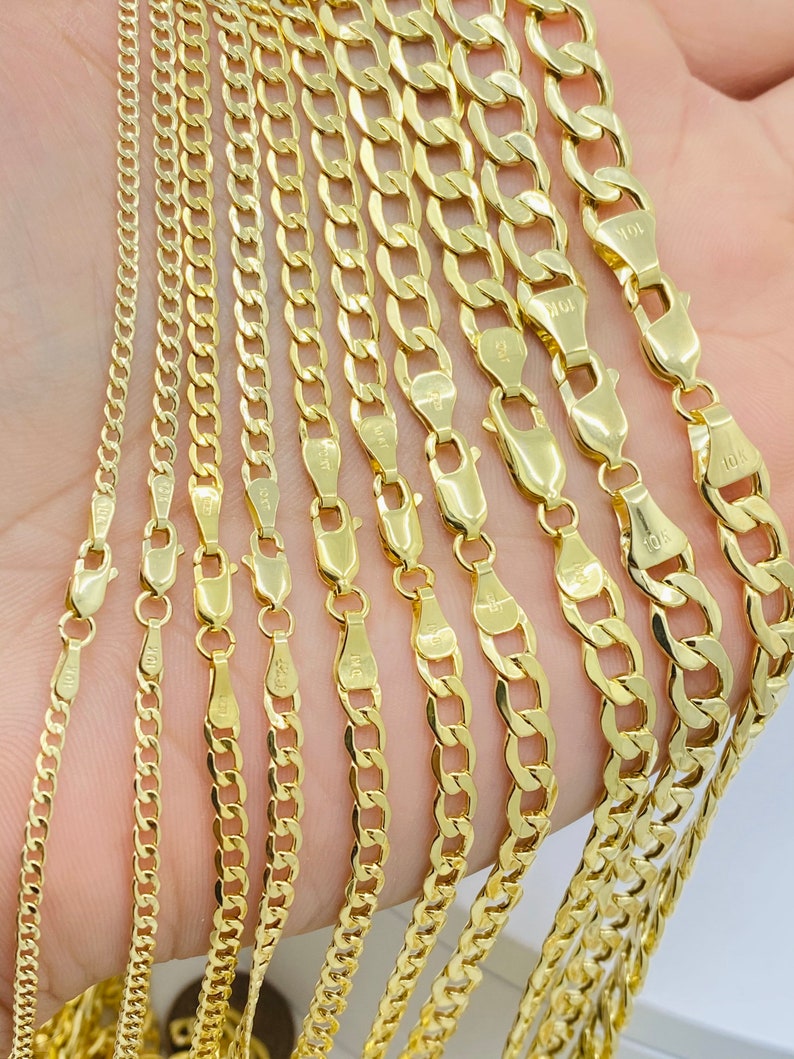 May include: A set of gold chains of varying widths and lengths. The chains are arranged in a fan shape, with the widest chain at the top and the narrowest chain at the bottom. The chains are all made of 10k gold.