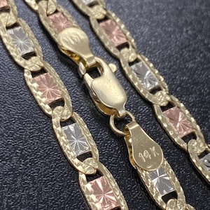 Puede incluir: Un collar de cadena de oro de tres tonos con un cierre de 14K. La cadena est&aacute; hecha de eslabones alternos de oro amarillo, blanco y rosa. Cada eslab&oacute;n tiene un dise&ntilde;o de estrella.