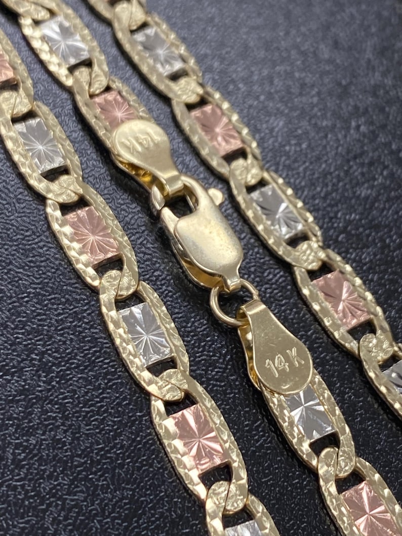 Puede incluir: Un collar de cadena de oro de tres tonos con un cierre de 14K. La cadena est&aacute; hecha de eslabones alternos de oro amarillo, blanco y rosa. Cada eslab&oacute;n tiene un dise&ntilde;o de estrella.