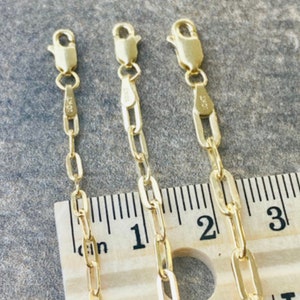 Pu&ograve; includere: Tre catene d'oro di diverse lunghezze, disposte su un righello di legno. Le catene sono composte da maglie ovali. Il righello &egrave; graduato in pollici.