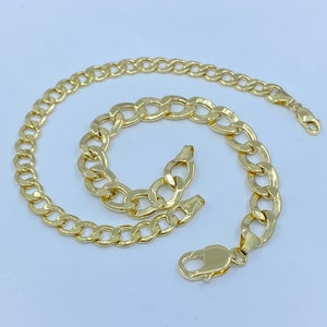 May include: A gold chain necklace and bracelet set with a curb link design.