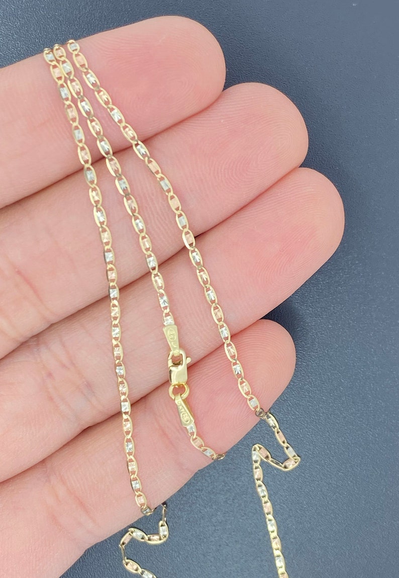 K&ouml;nnte beinhalten: Eine goldene Kettenkette mit dreifarbigem Design. Die Kette ist aus Gelb-, Wei&szlig;- und Ros&eacute;gold.