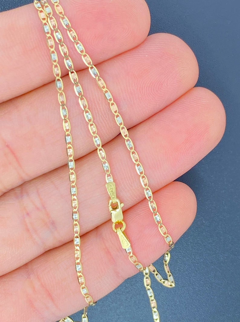 K&ouml;nnte beinhalten: Eine goldene Kettenkette mit drei verschiedenen farbigen Gliedern. Die Kette ist aus Gelb-, Wei&szlig;- und Ros&eacute;gold gefertigt. Die Kette liegt auf einer Hand.