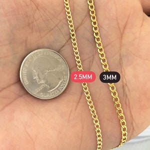 May include: Two gold chains, one 2.5mm and one 3mm thick, are laid out on a hand for comparison. The chains are both Cuban link style.