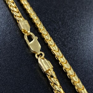May include: A gold chain necklace with a 24K stamp on the clasp. The chain is a classic, flat, box style.
