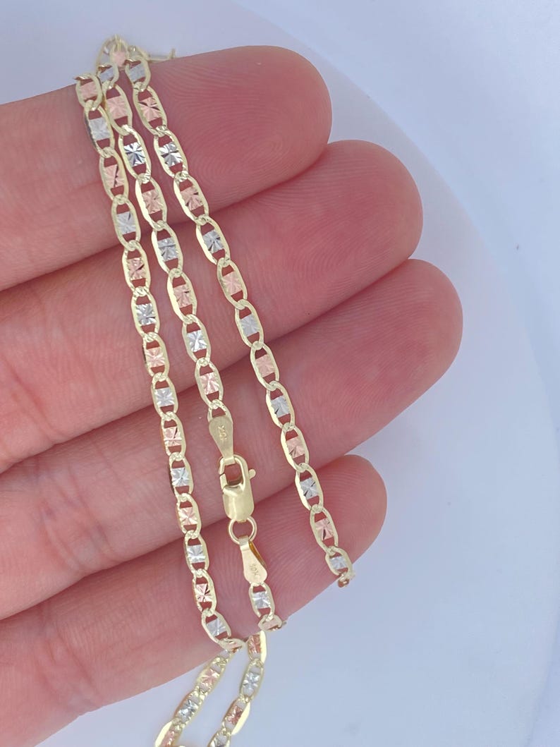 K&ouml;nnte beinhalten: Eine goldene Halskette mit filigranem Kettendesign. Die Kette hat abwechselnd Glieder aus Gelb-, Wei&szlig;- und Ros&eacute;gold. Die Halskette wird mit einem Karabinerverschluss gesichert. Die Kette ist etwa 45 cm lang.