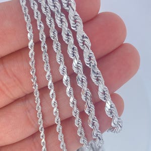 May include: A collection of silver-colored rope chains of varying thicknesses. The chains are displayed against a light background, showcasing their twisted design and reflective surface. The image highlights the different sizes available.