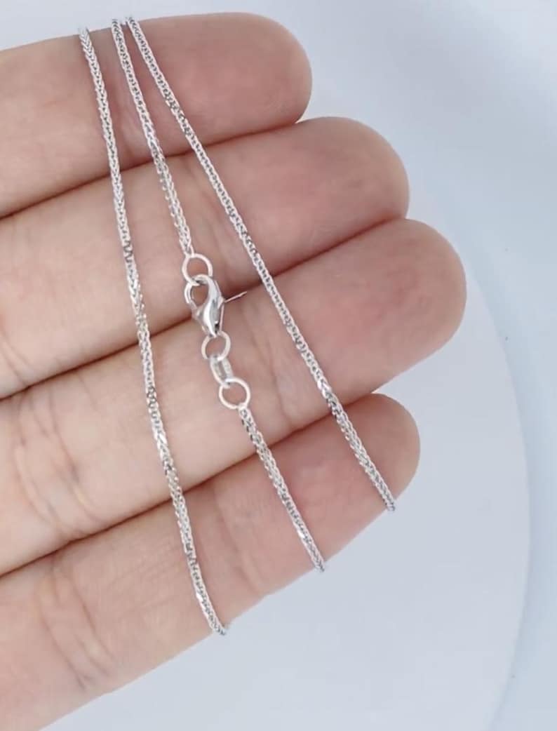 May include: A silver chain necklace with a lobster clasp. The chain is a delicate, braided design.