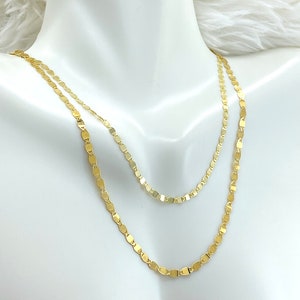 May include: Two gold chains with a flat oval link design. The chains are layered on a white mannequin.