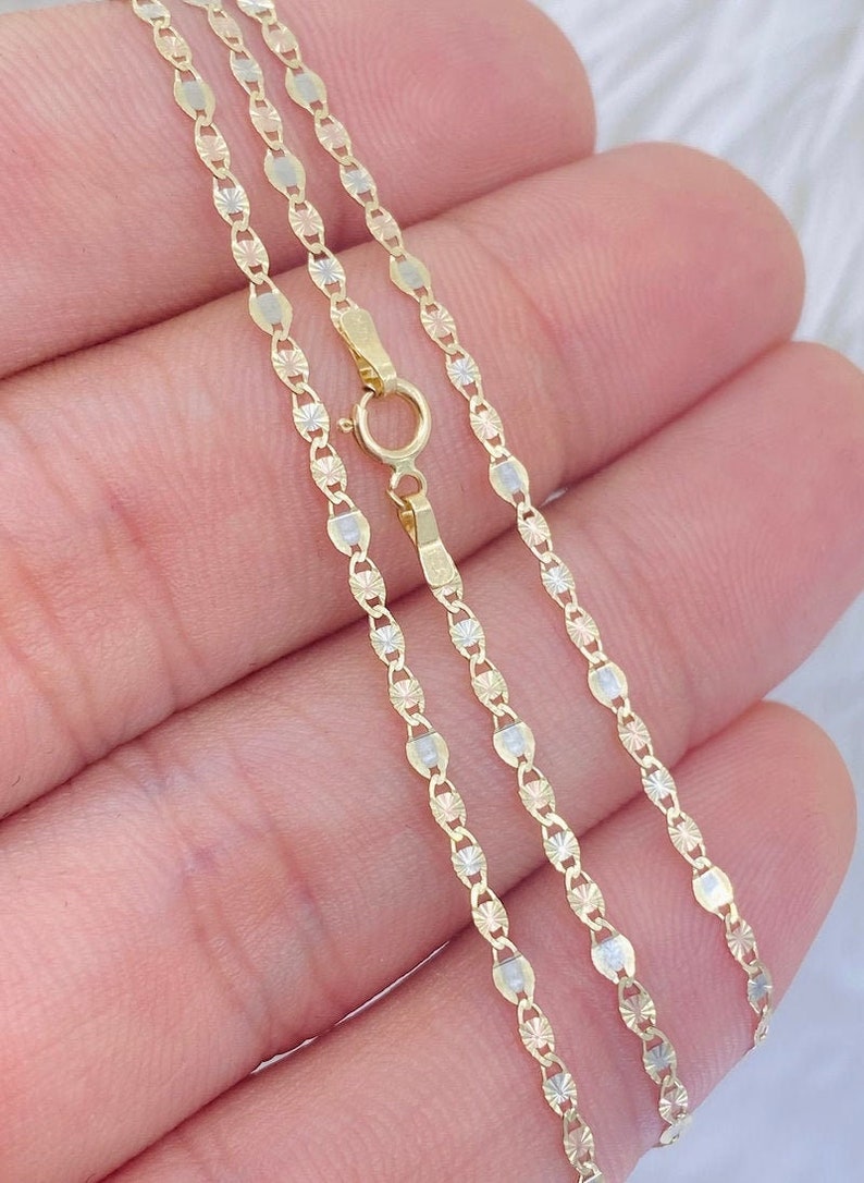 May include: A gold chain necklace with a delicate, patterned design. The chain is made of three different shades of gold, creating a unique and stylish look.
