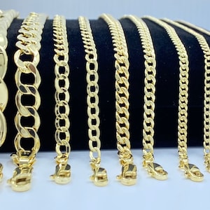 May include: A set of ten gold chains of varying widths and lengths displayed on a black velvet background. The chains are all made of a solid gold material and have a classic curb chain design.
