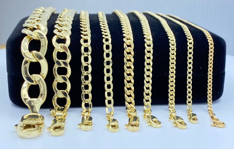 May include: A set of ten gold chains of varying widths and lengths displayed on a black velvet background. The chains are all made of a solid gold material and have a classic curb chain design.