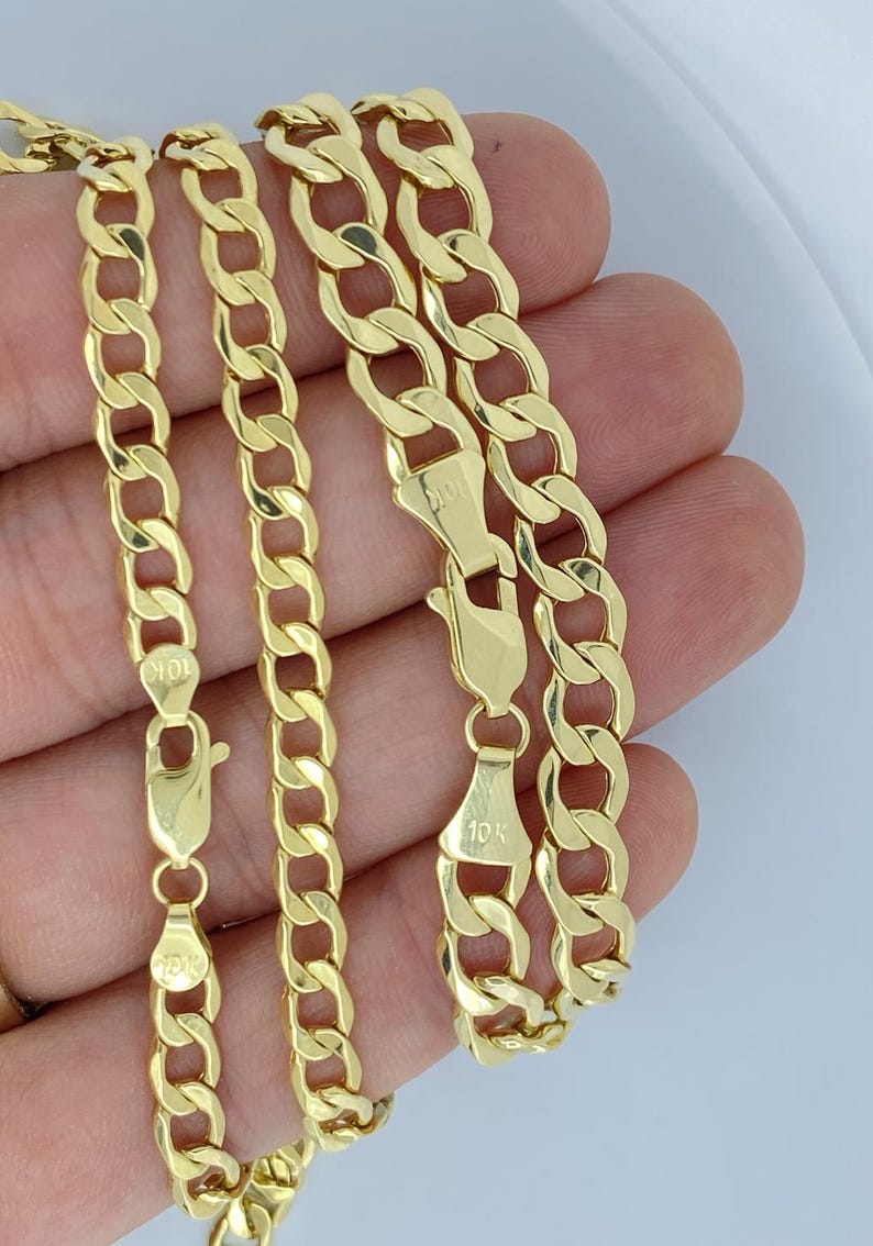May include: Three gold chains with a curb link pattern. The chains are 10k gold and have a lobster clasp.