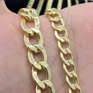 May include: Two gold chains, one thicker than the other, are shown on a hand. Both chains are made of a classic curb link style.