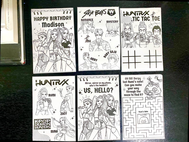 May include: A collection of white cards with black line art illustrations. The cards feature various designs, including portraits, text, and a tic-tac-toe game. Some cards have text like "HAPPY BIRTHDAY Madison" and "US, HELLO?"