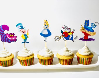 May include: Six cupcakes with white frosting and colorful wrappers. Each cupcake has a different Alice in Wonderland character topper: the Cheshire Cat, the Mad Hatter, Alice, the White Rabbit, and the Queen of Hearts.