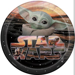 May include: A round paper plate with a black background and a white "Star Wars" logo. The logo is layered with images of characters from the Star Wars franchise, including a Mandalorian and a Baby Yoda. The background is a sunset scene with stars.