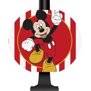 May include: A red and white striped circle with a gold outline featuring Mickey Mouse in a red and black outfit. Mickey Mouse is smiling and waving with his right hand raised. The circle is attached to a black plastic party noisemaker.